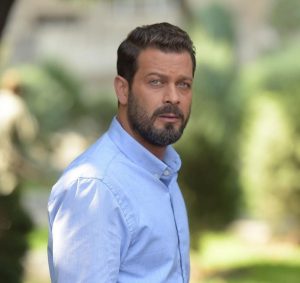 پژمان بازغی در یک فضای سبز با پیرهن مردانه ی آبی رنگ