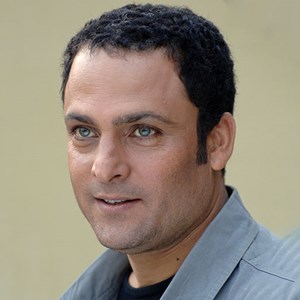 عکس پرتره حسین یاری با لباس طوسی و چشمان آبی رنگش